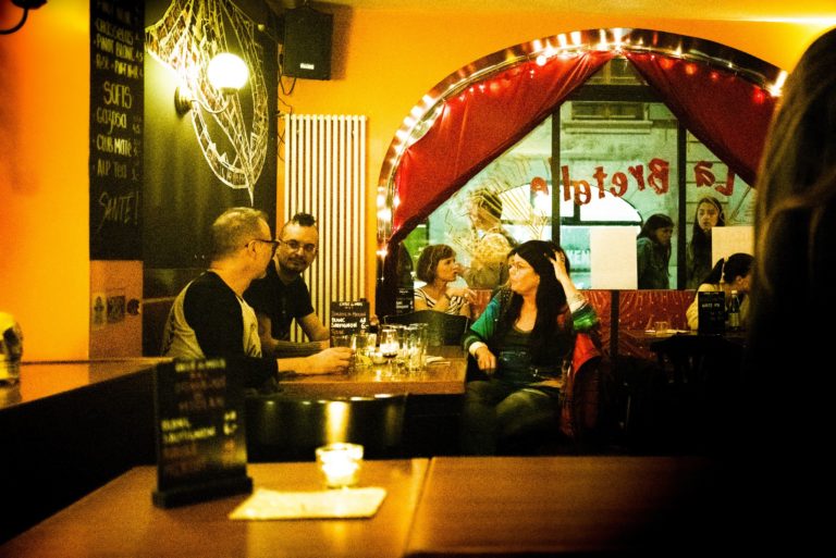 La salle du bar, des clients attablés sous l’arche rouge