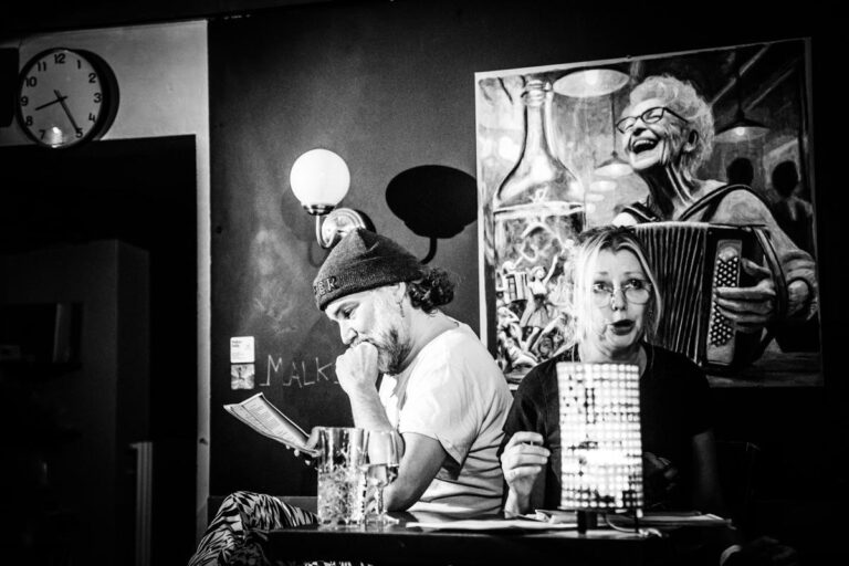 Lecture à une table du bar, sous le grand portrait d’une accordéoniste